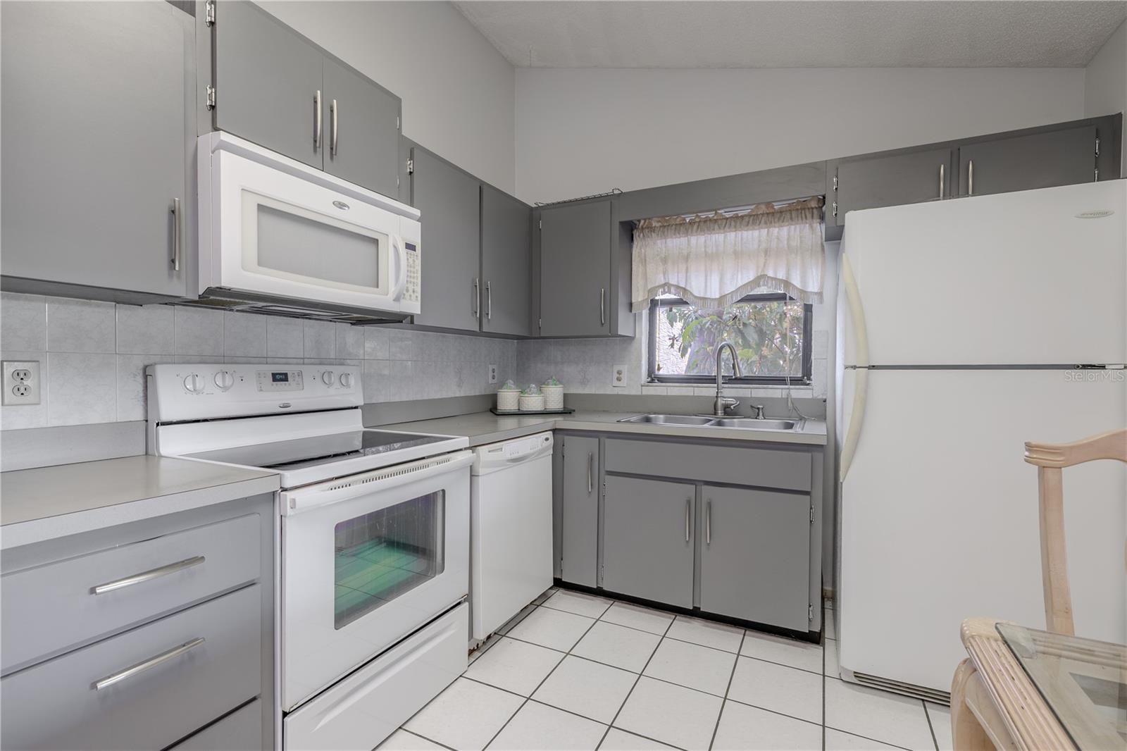 The kitchen features appliances including range, microwave and refrigerator, a tile floor, a window above the sink and room for your breakfast table.