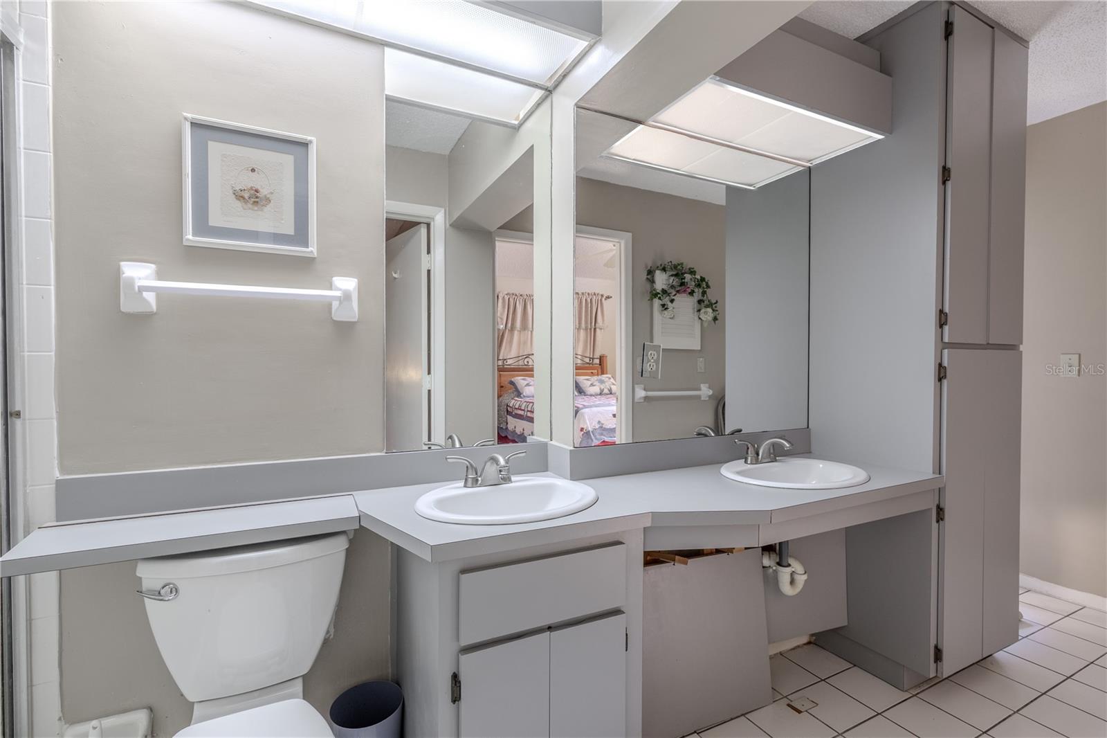 The primary bath features a mirrored dual sink vanity with storage.