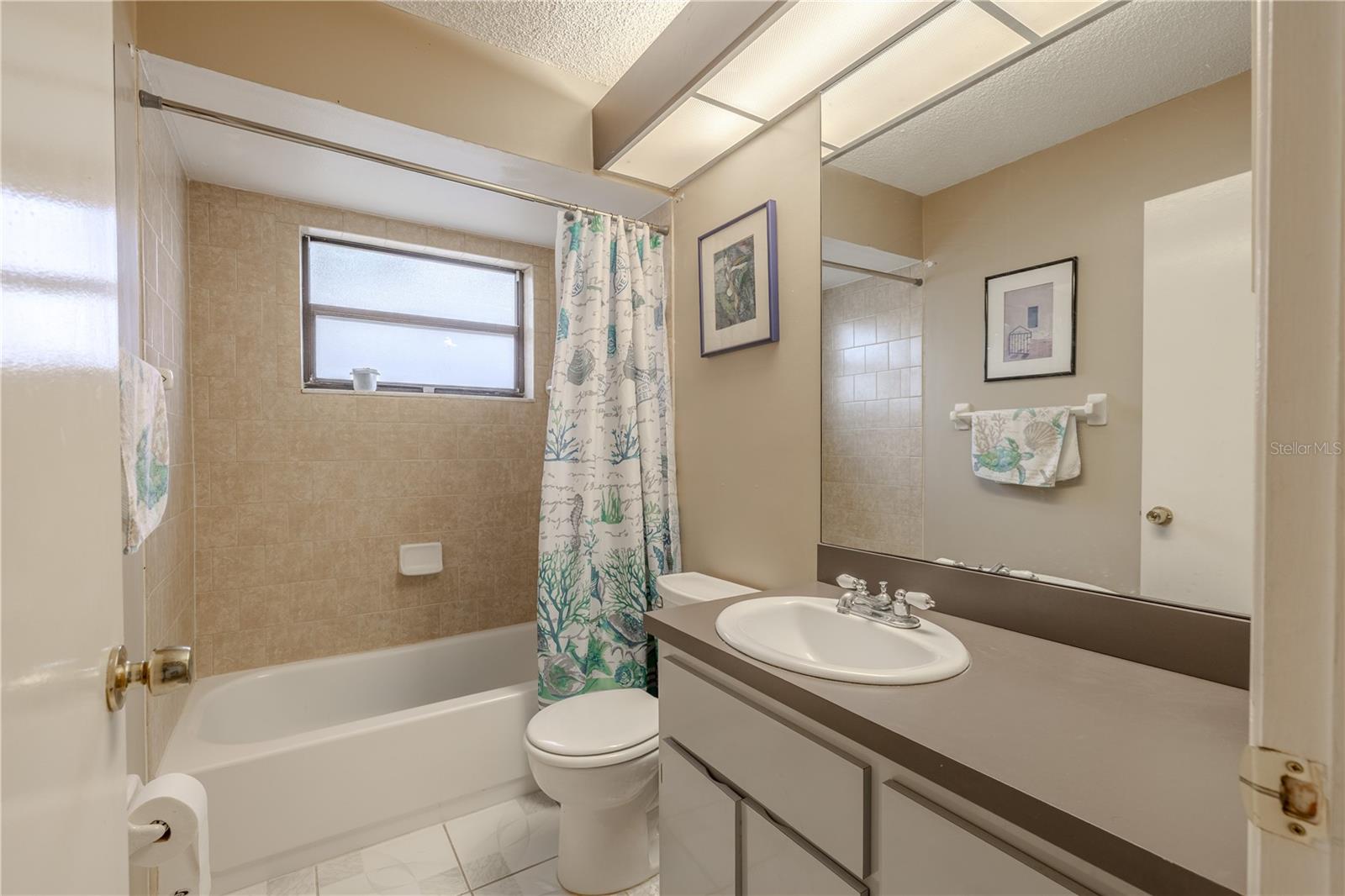 Bathroom 2 features a single mirrored vanity with storage, a tile floor and a tub with shower.