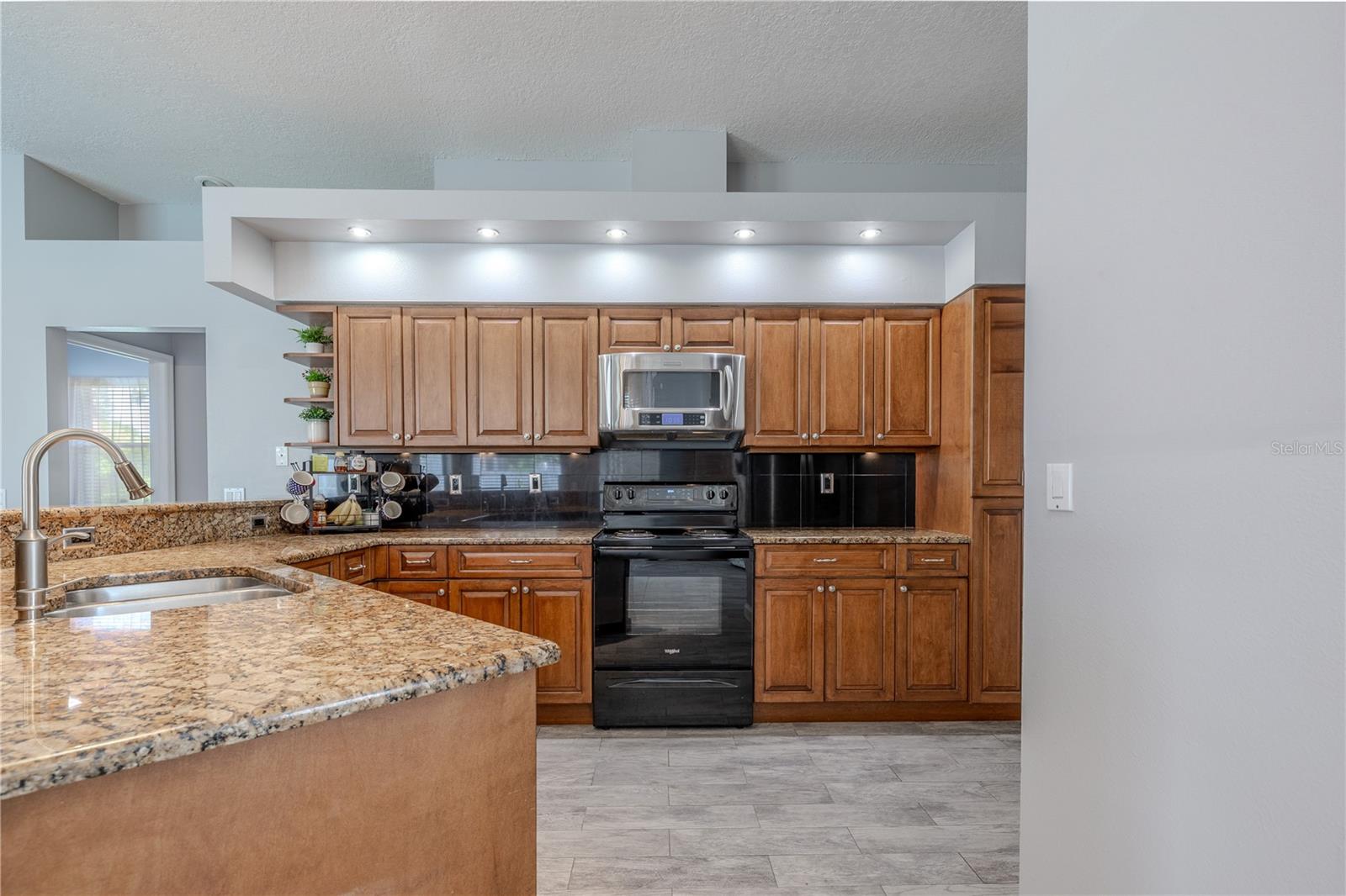 The kitchen features wood cabinets, granite counters and recessed lighting.