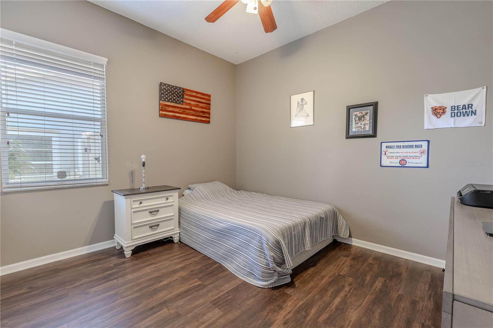 Bedroom 2 features neutral tones, engineered hardwood flooring, a built in closet and a ceiling fan with light kit.