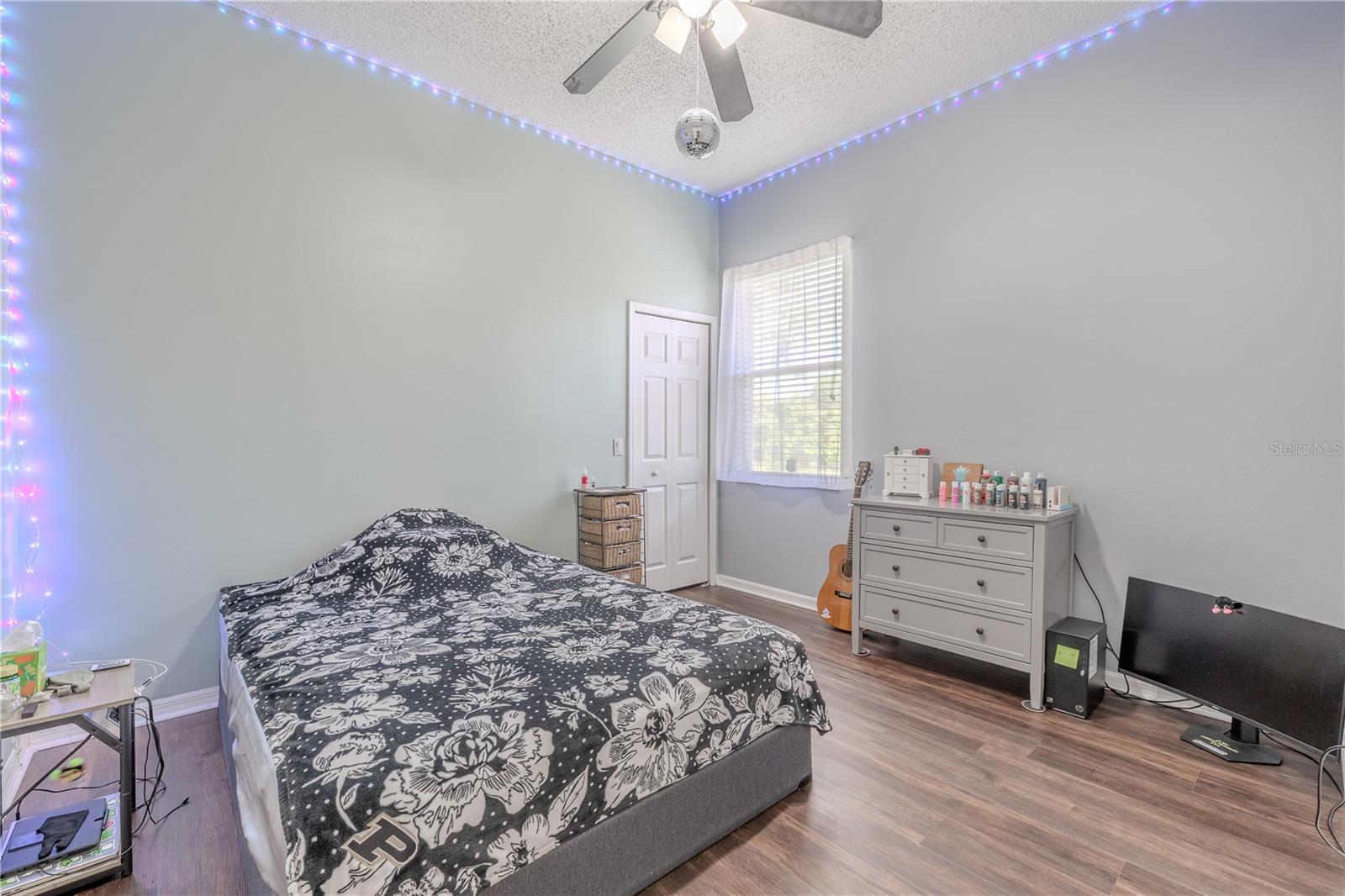 Bedroom 3 features neutral tones, engineered hardwood flooring, a built in closet and a ceiling fan with light kit.