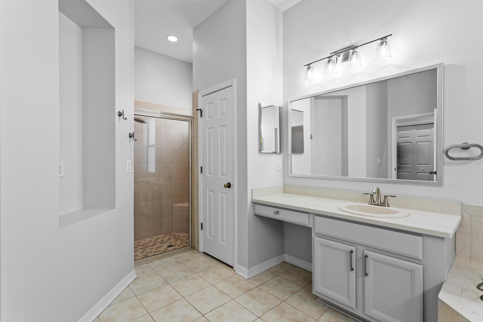 The primary bath has updated mirrors, light fixtures and new plumbing hardware along with a walk-in shower