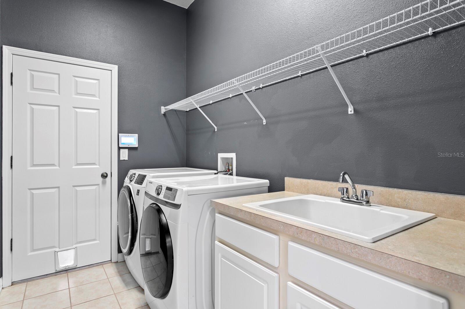 The oversized laundry room includes a utility sink and cabinets and leads out to the oversized 2-car garage