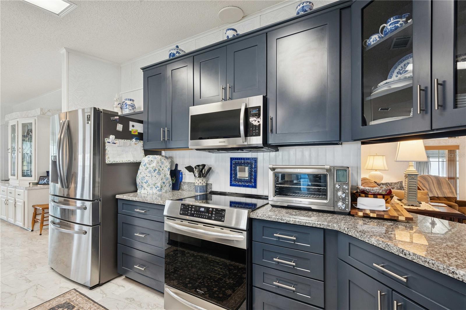 Stainless steel appliances, four-door refrigerator, convection oven, and custom backsplash.