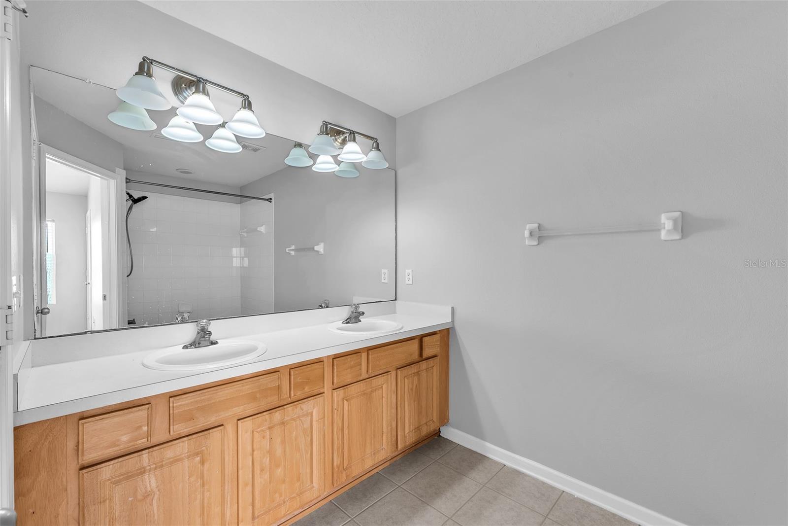 The primary en-suite bathroom has a long vanity with dual sinks, a tub/shower combination and a private water closet.