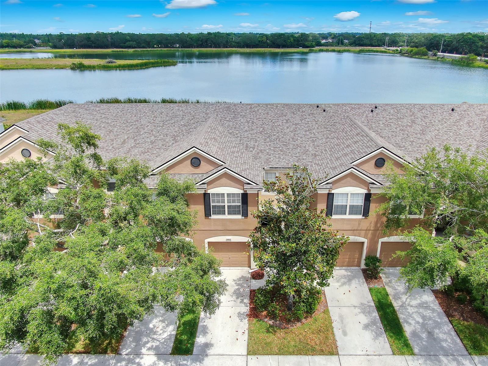 Aerial view of front of townhome and water in back.