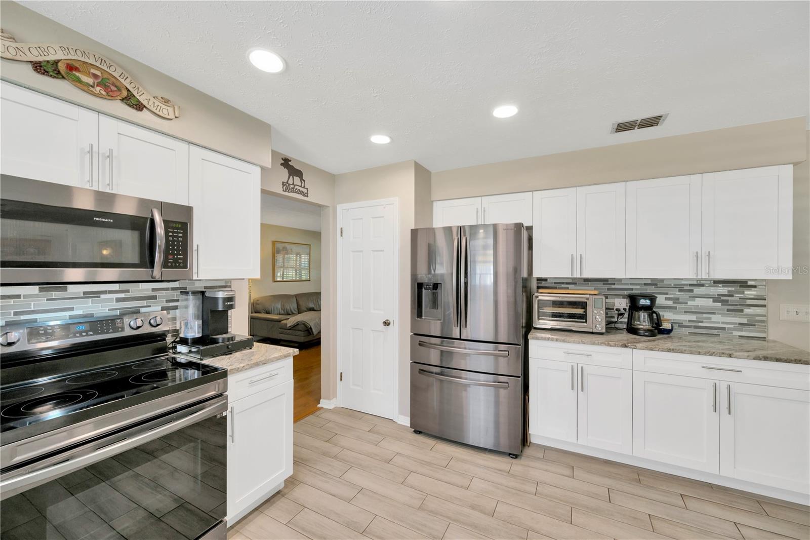 The kitchen features black stainless steel appliances, plenty of stylish granite countertops, a sea glass backsplash, and a closet pantry for additional storage.