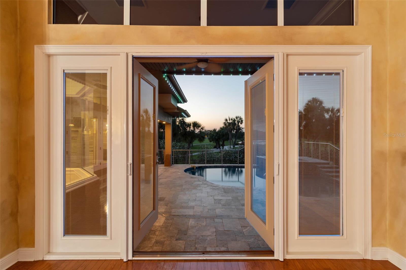 Doors from the living room to the pool area at sunset.