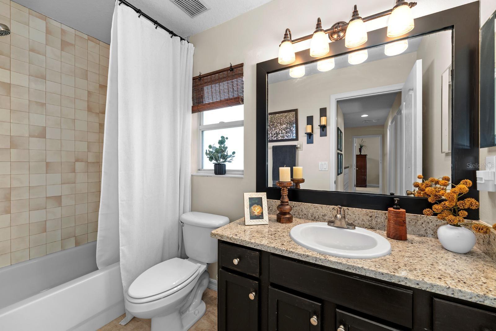 The secondary bathroom features updated lighting, a beautiful new mirror, updated tile in the shower, newer tile flooring, and a granite countertop!!!