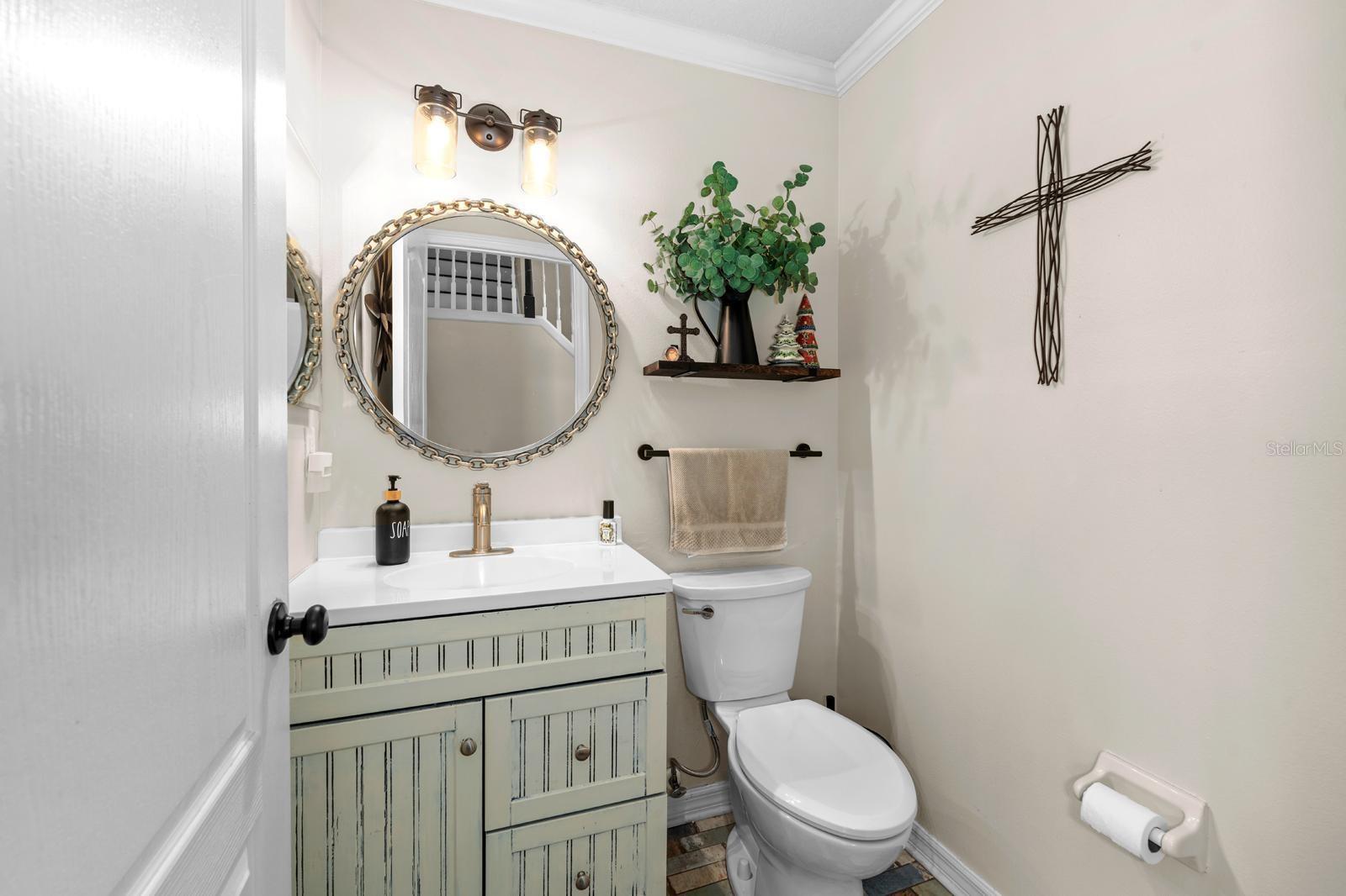 The half bath downstairs has a newer vanity and faucet, new lighting, an adorable mirror, crown molding, and fun brick flooring.