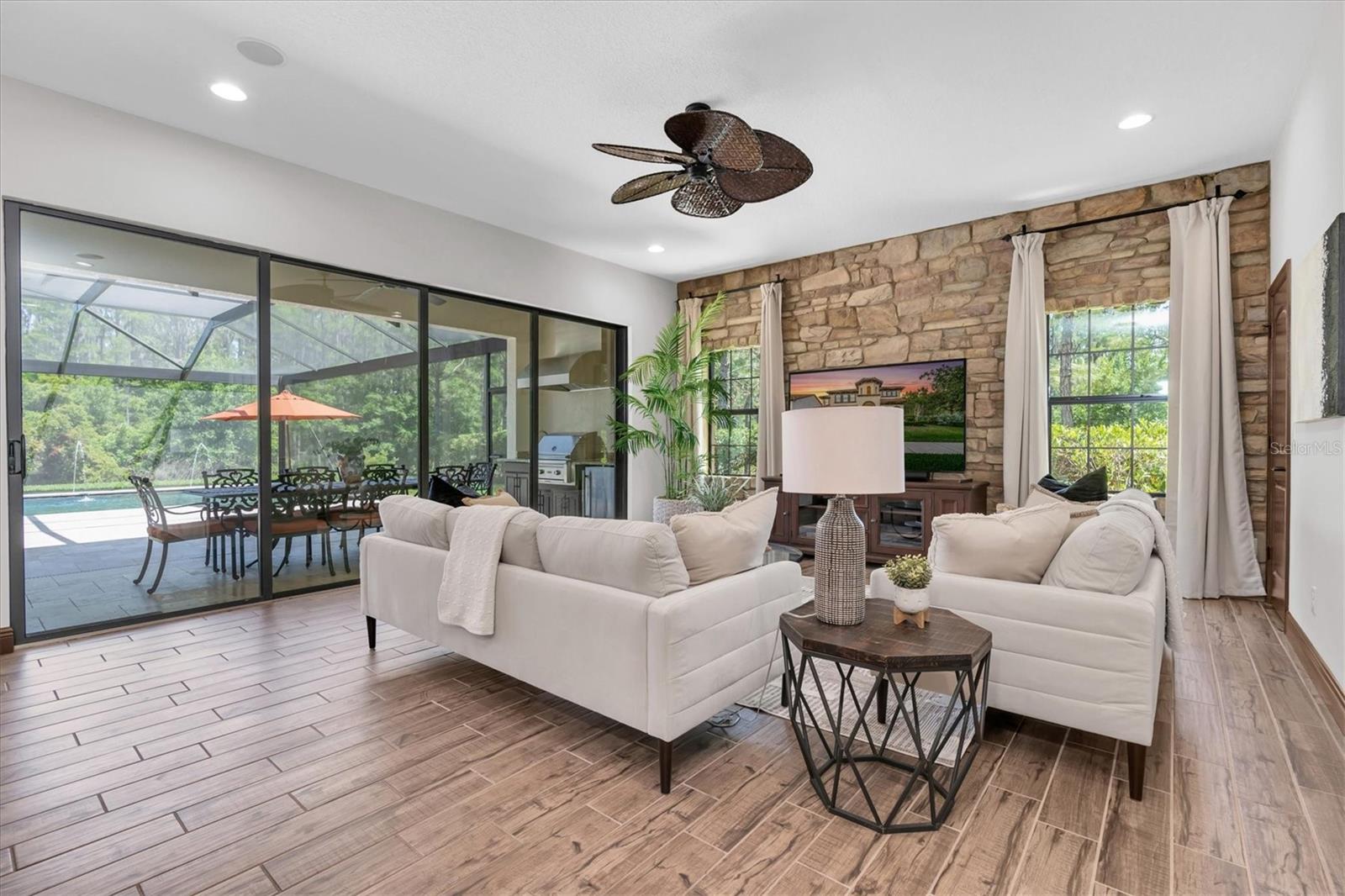 GATHER IN THE GRAND ROOM ANCHORED BY CUSTOM ACCENT STONE WALL