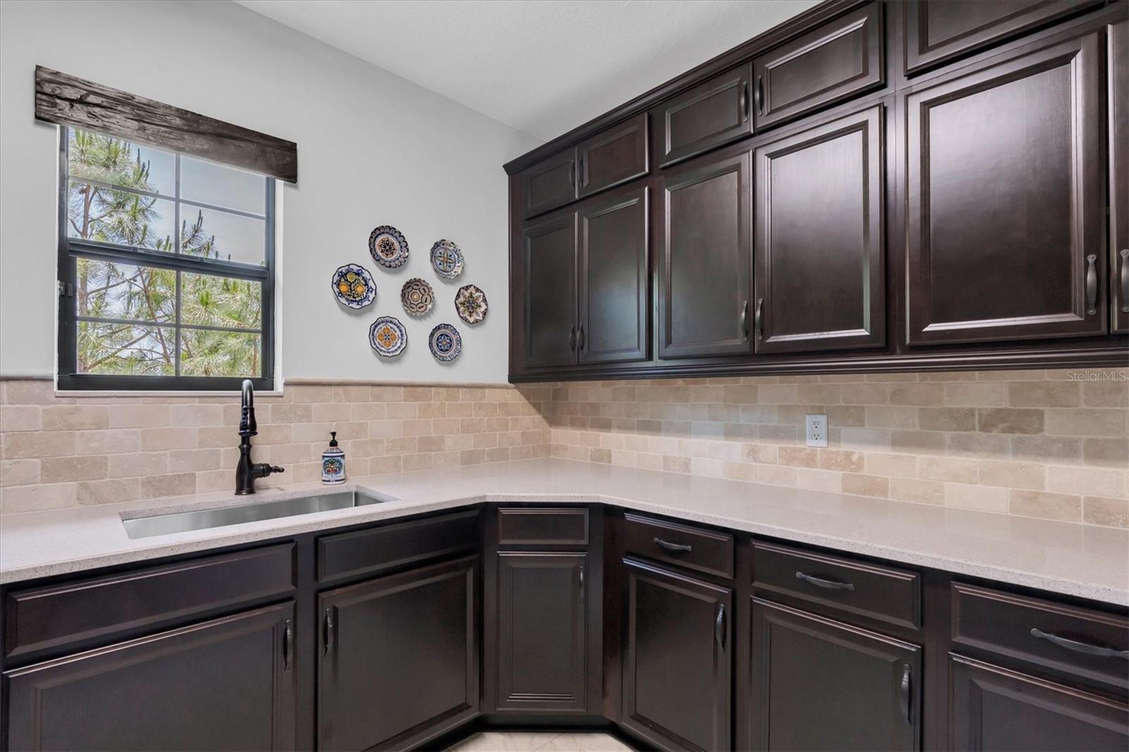 LAUNDRY ROOM WITH QUARTZ COUNTERS, TRAVERTINE BACKSPLASH & SINK