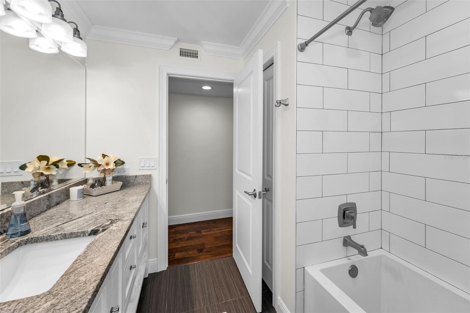 Guest bath has a large vanity for storage plus a large linen closet. Deep tub with shower