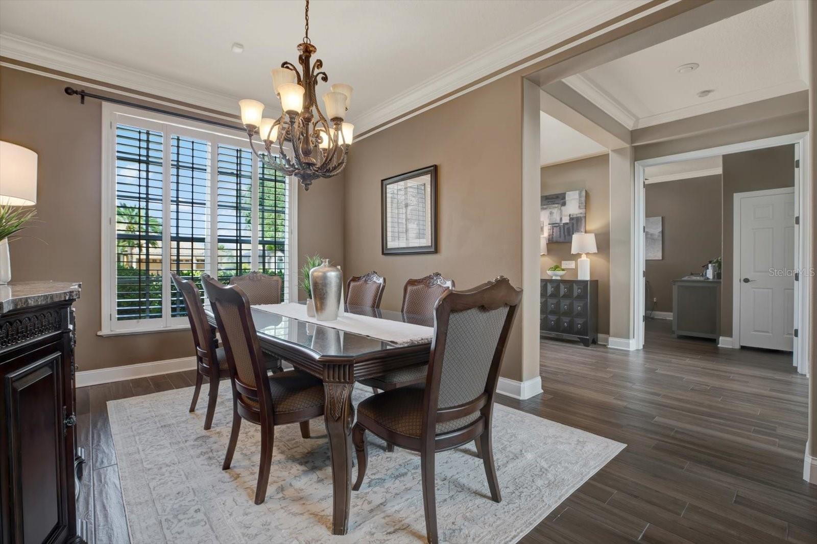 Formal dining room off the entrance features crown molding and plantation shutters.