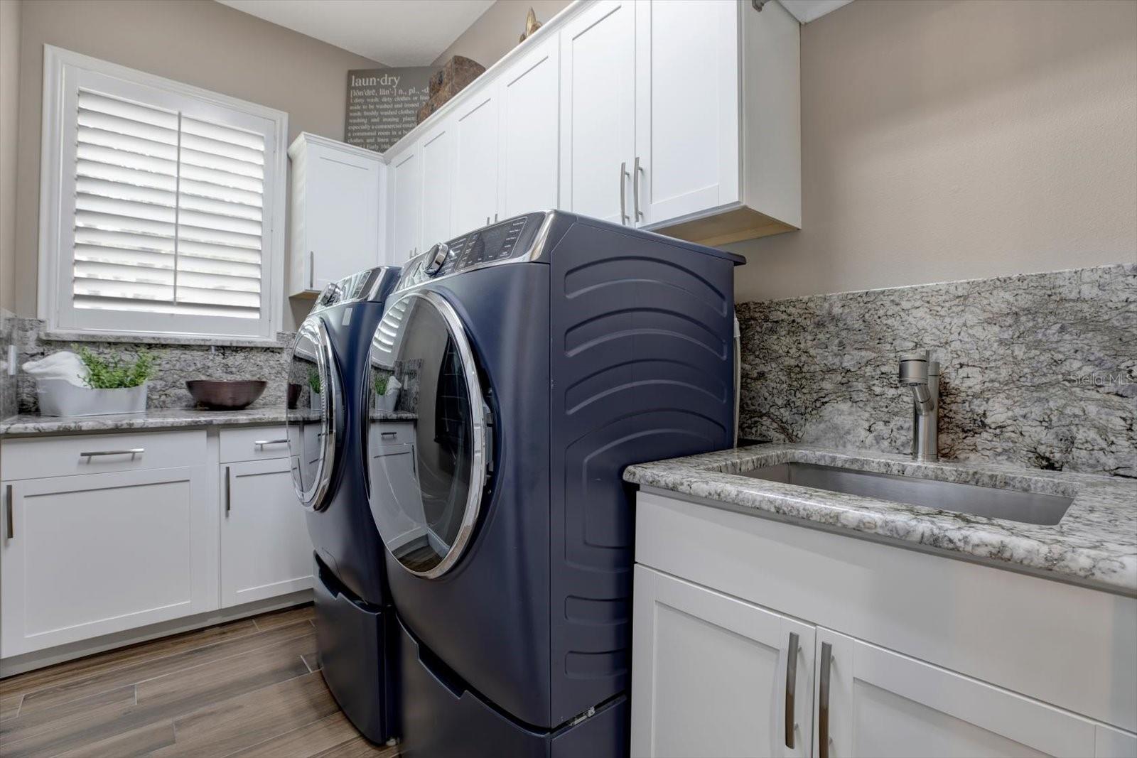 Laundry room with wash sink, cabinets and counter space. Washer & dryer convey.