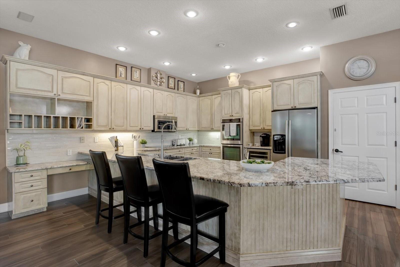 Open concept kitchen with stainless steel appliances, granite countertops, large panty and built in desk area.