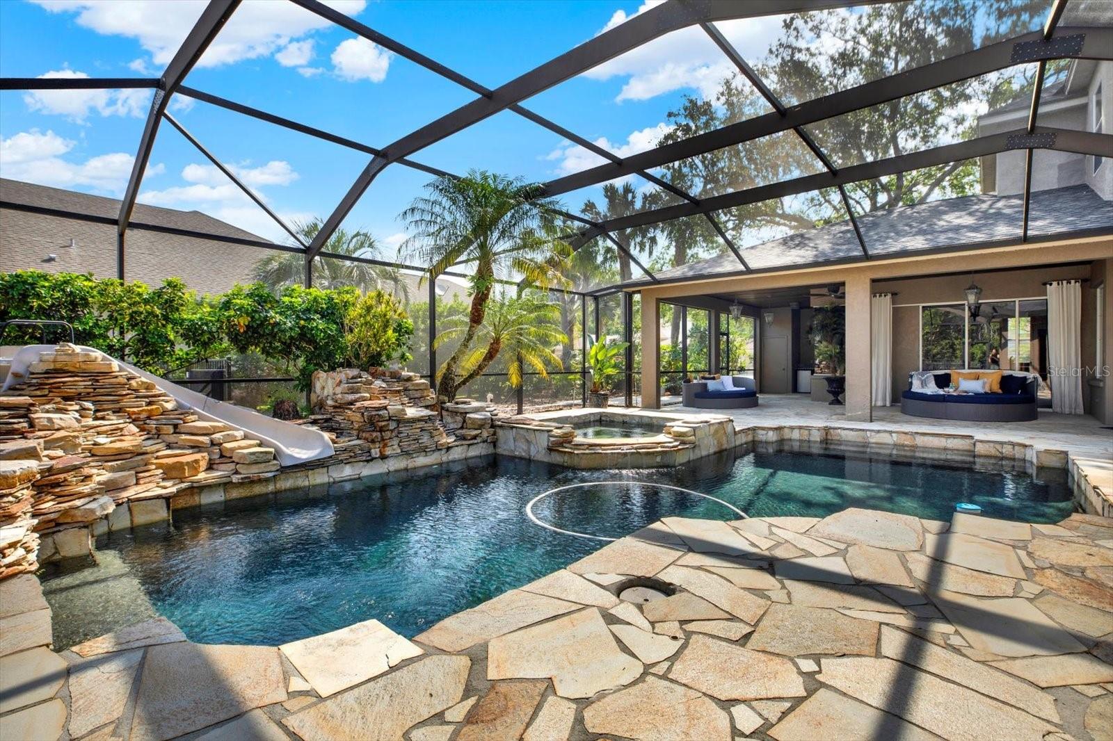 The entire bottom level surrounds this gorgeous tropical pool with slide, jacuzzi/waterfall feature and large wrap around lanai with wet bar and entrance to pool bath. Perfect for entertaining!