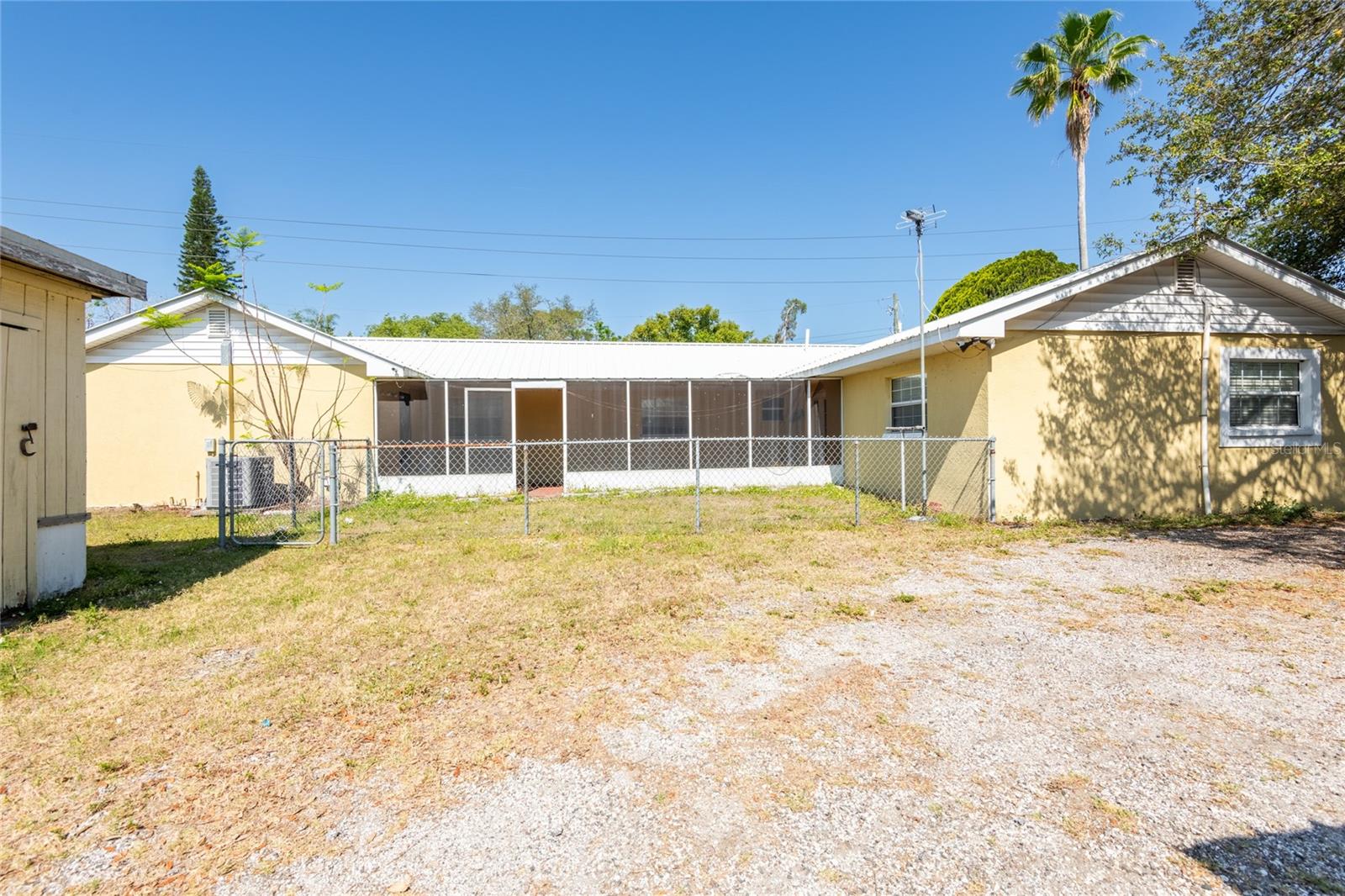 Side of house, screened lanai & small fenced yard