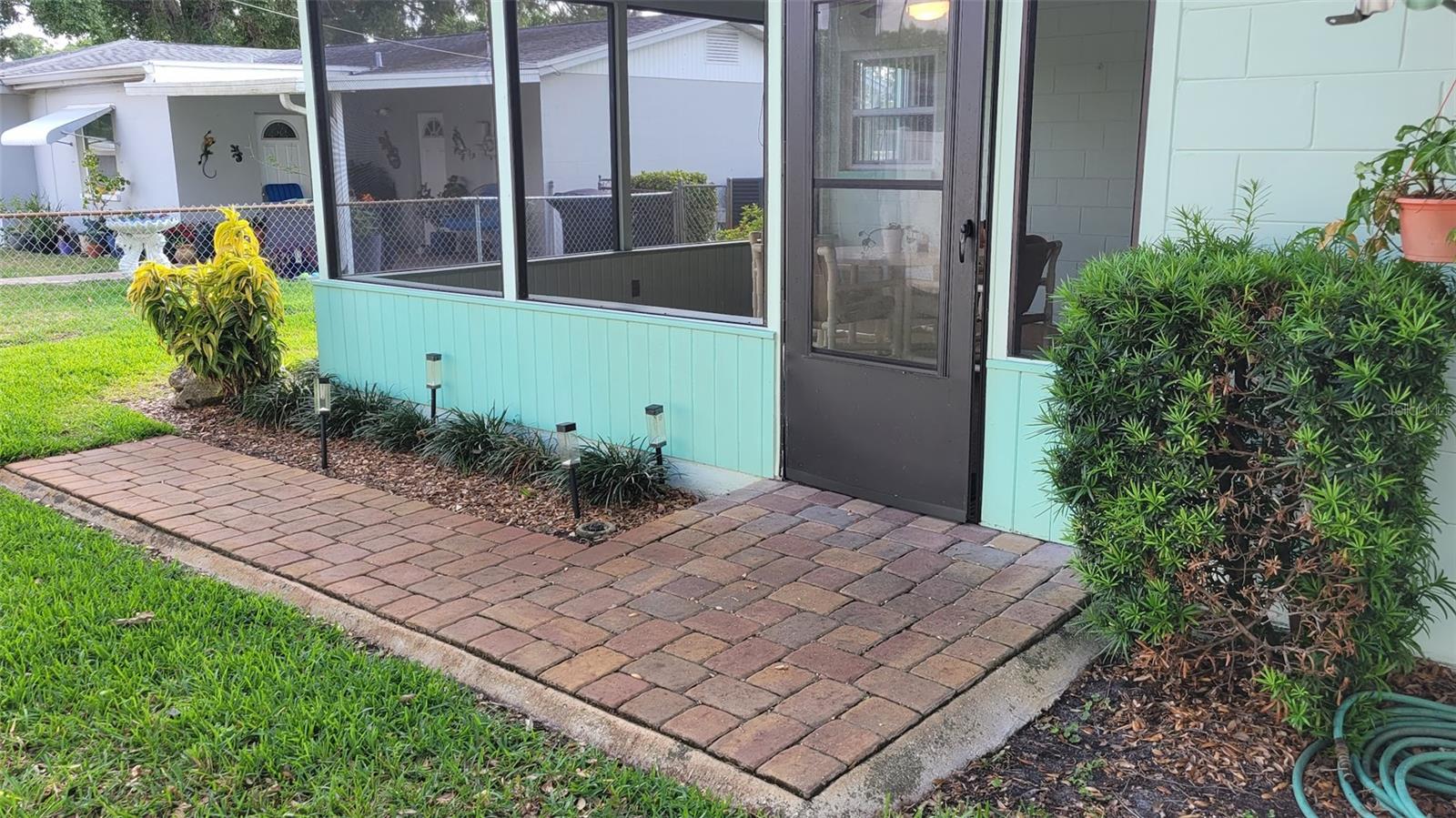 The entry to the screened patio is in the back of the home and has beautiful pavers leading to it.