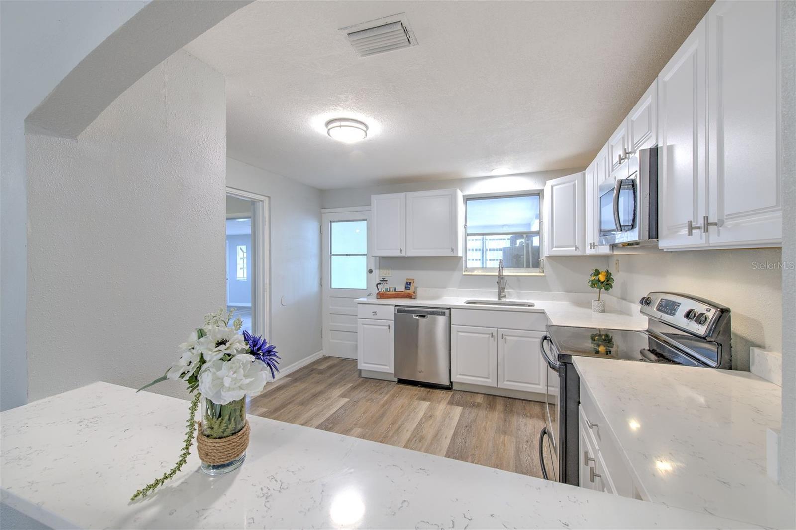 gourmet kitchen with breakfast area, quatz countertop, new cabinets, stainless steel appliances. behind kitchen is the laundry room.