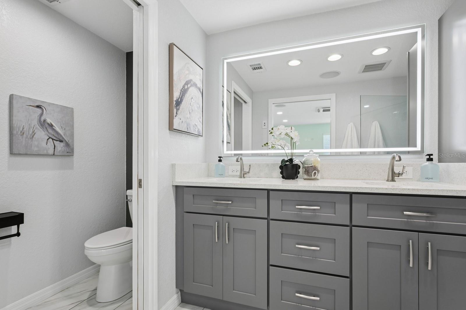 Primary bathroom with double sinks, water closet, and stand up shower