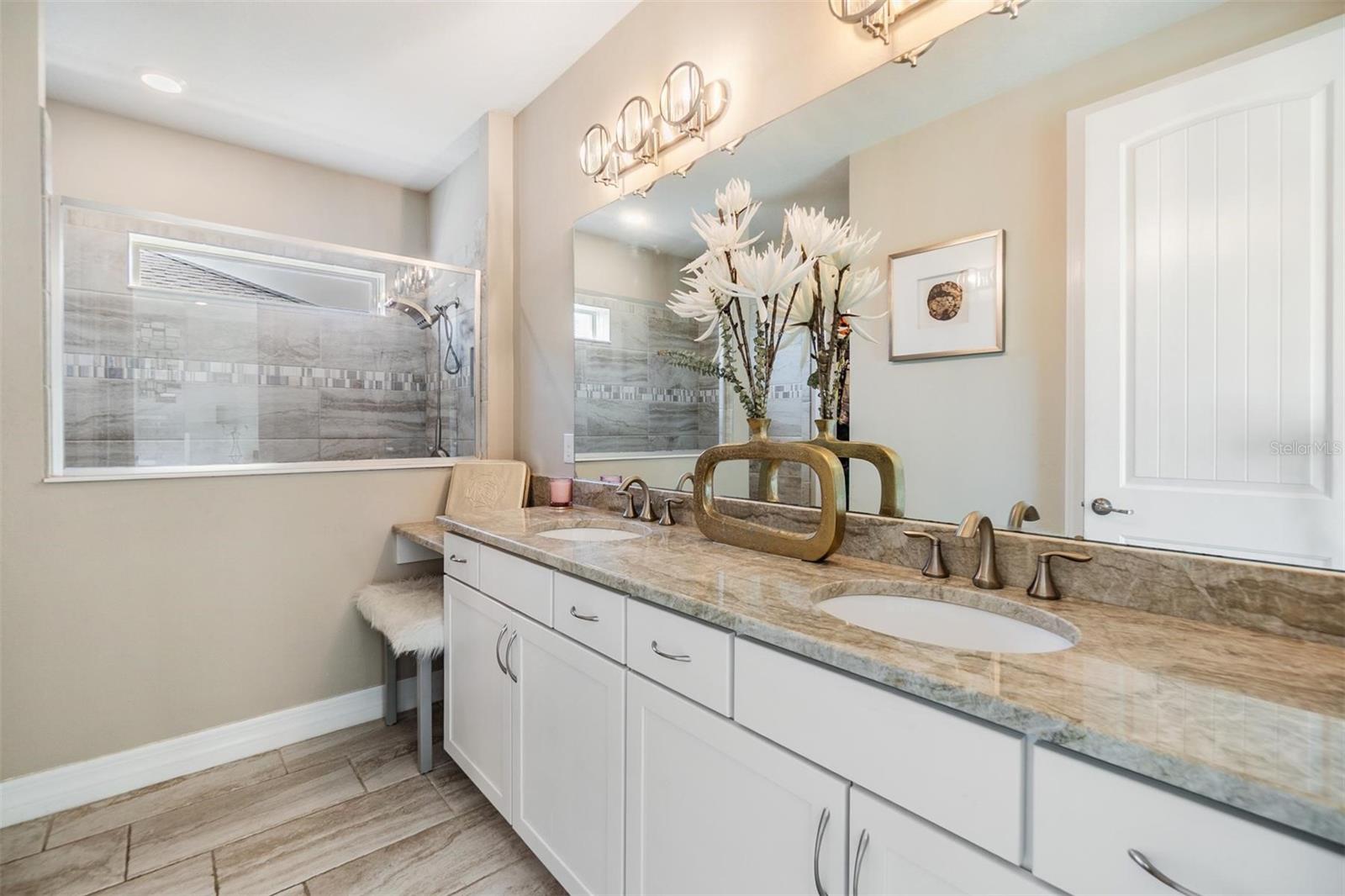 primary en-suite bath with double sink vanity,  makeup vanity space, and spa-like walk in shower