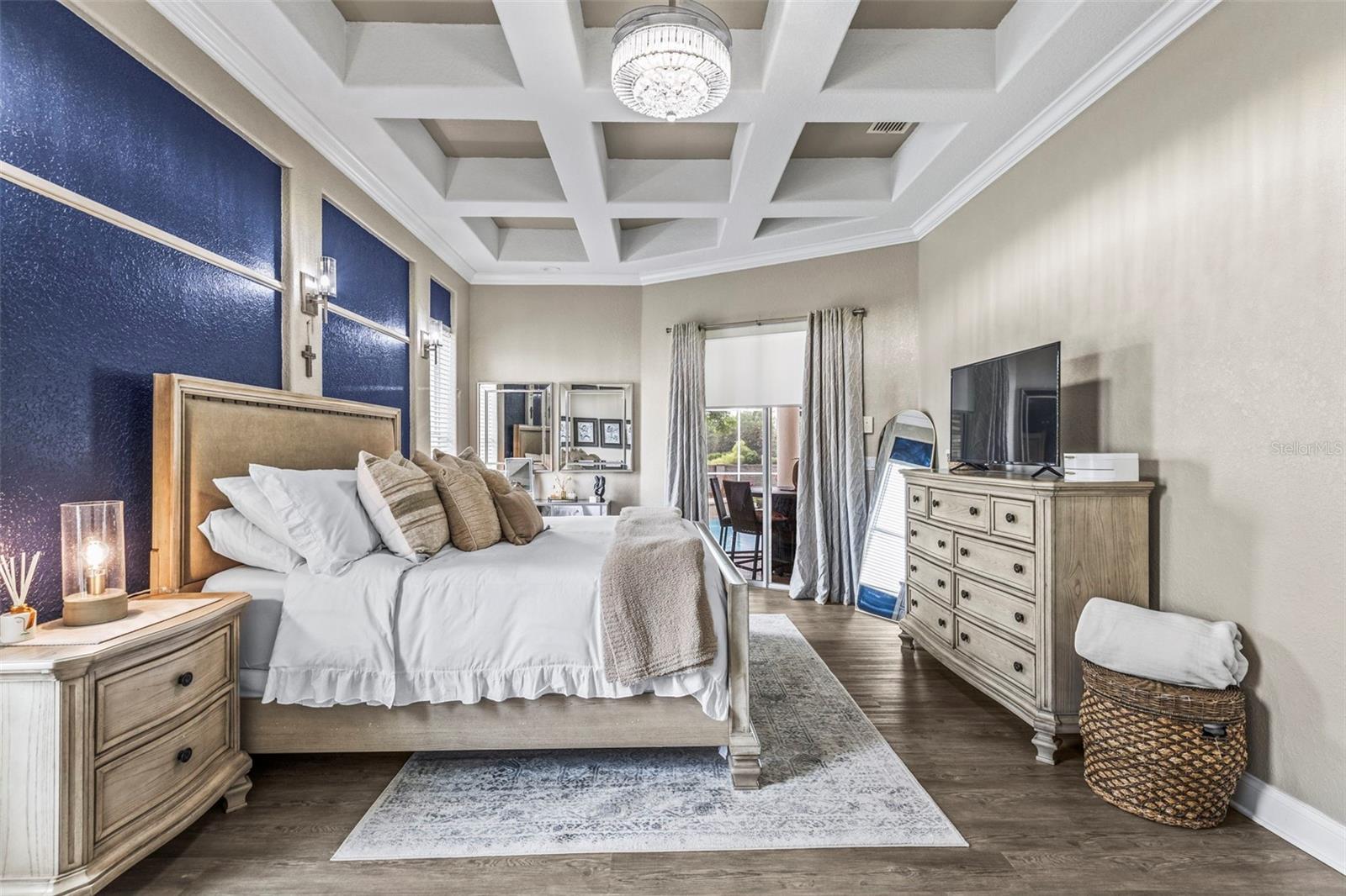 Primary bedroom with tray ceiling and sliding door access to the pool area