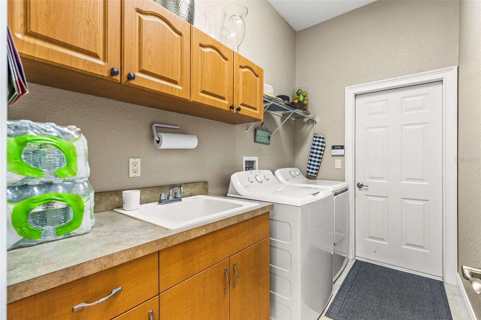 Walk through laundry area between the kitchen and garage with built in cabinets with sink
