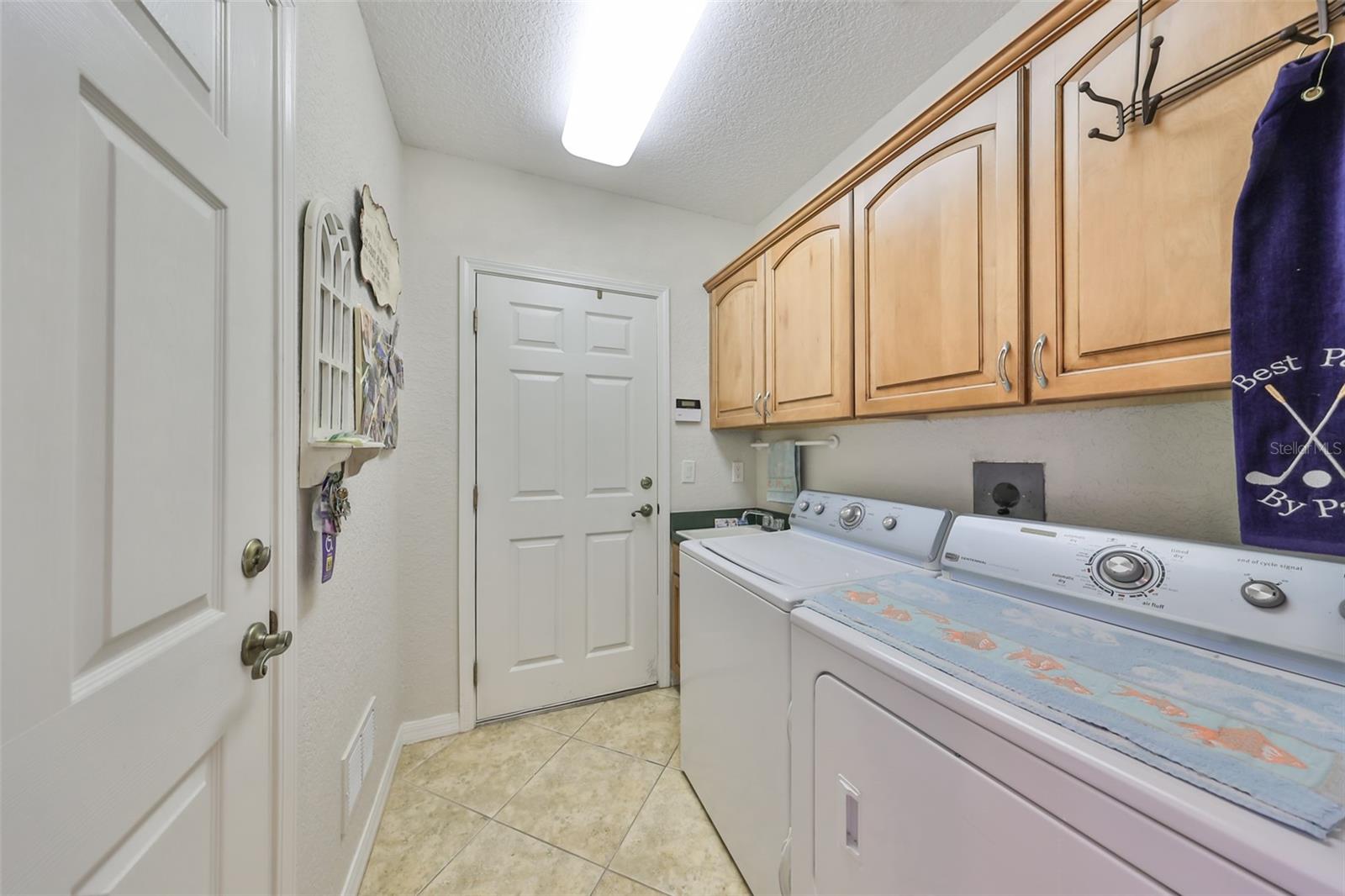 The laundry room is large with a utility sink and beautiful cabinetry for storage.