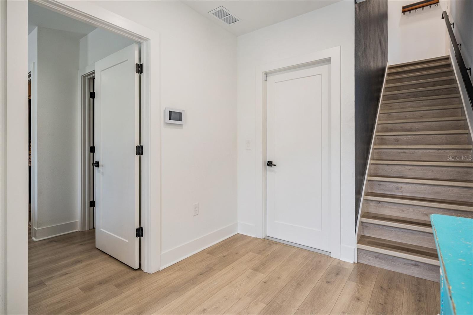Foyer showing rear garage door entrance, entrance into the downstairs bedroom suite and stairs up to the second floor.
