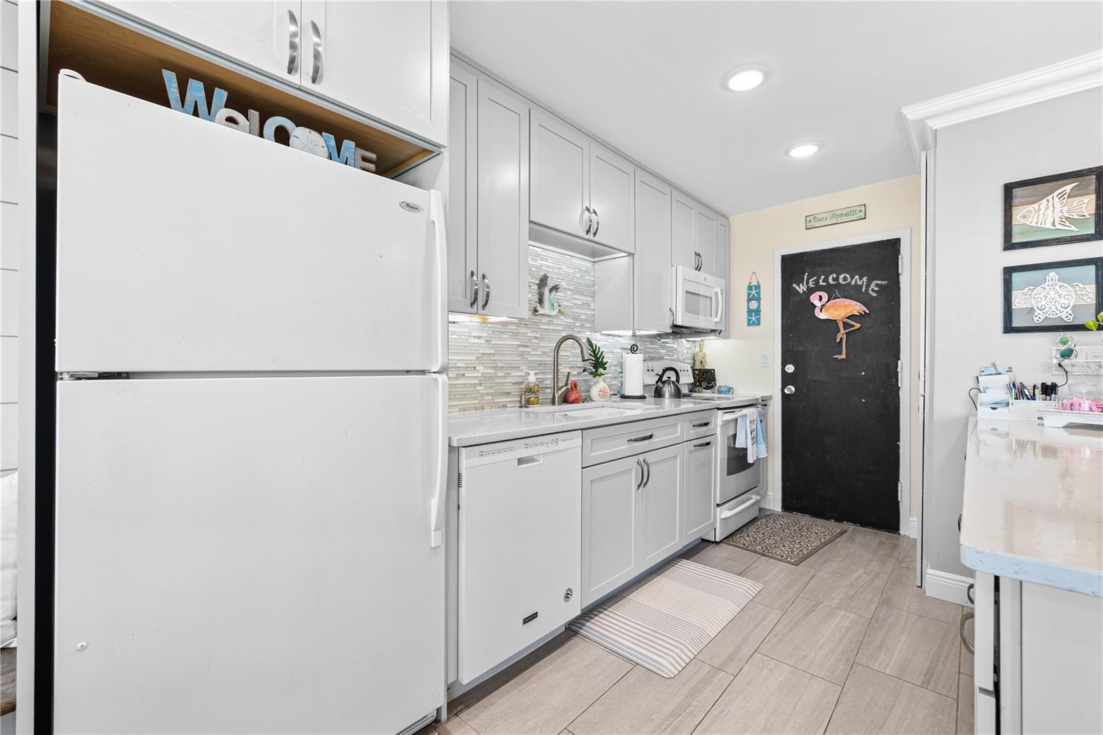 Renovated kitchen features cushion-close, shaker style cabinetry, granite countertops and gorgeous tile backsplash.