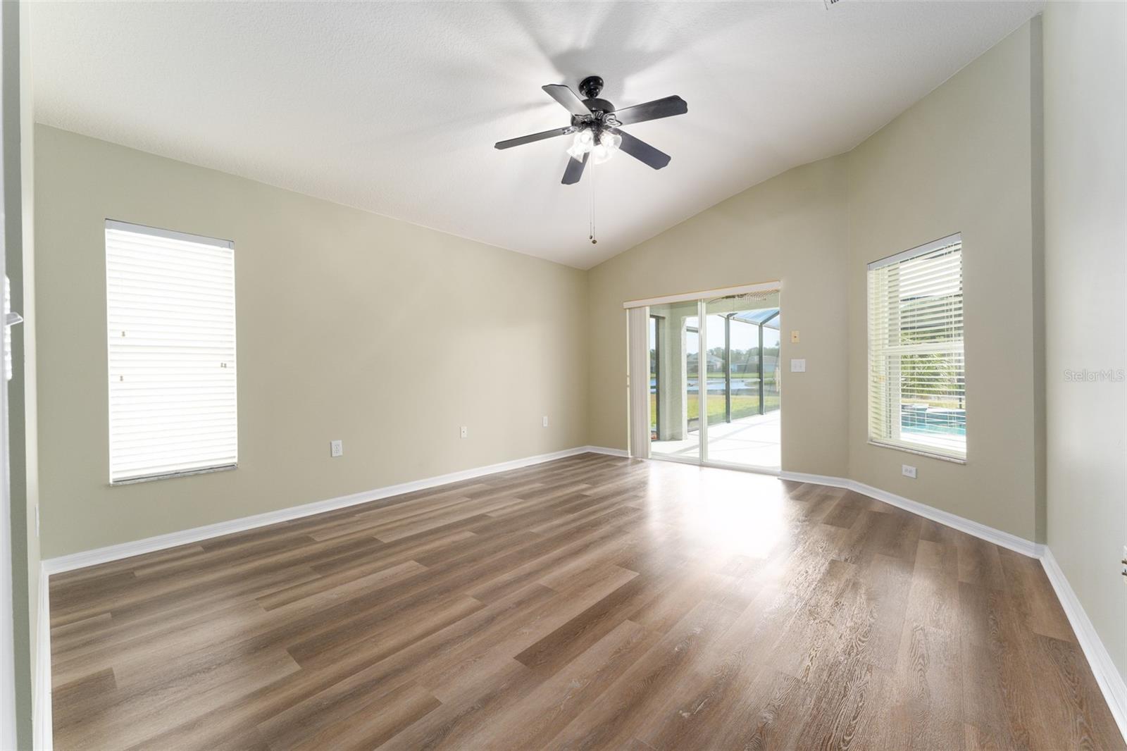 primary suite with new LVP flooring & private sliding glasses doors out to the lanai to access the pool & spa