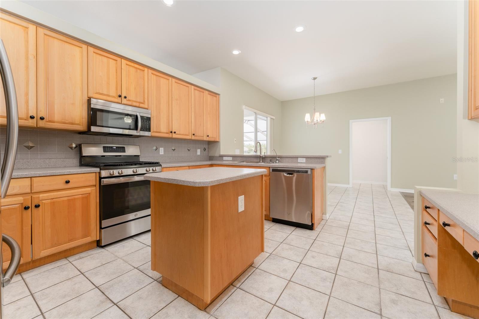 beautiful kitchen with stainless steel appliances, center island, desk & backsplash