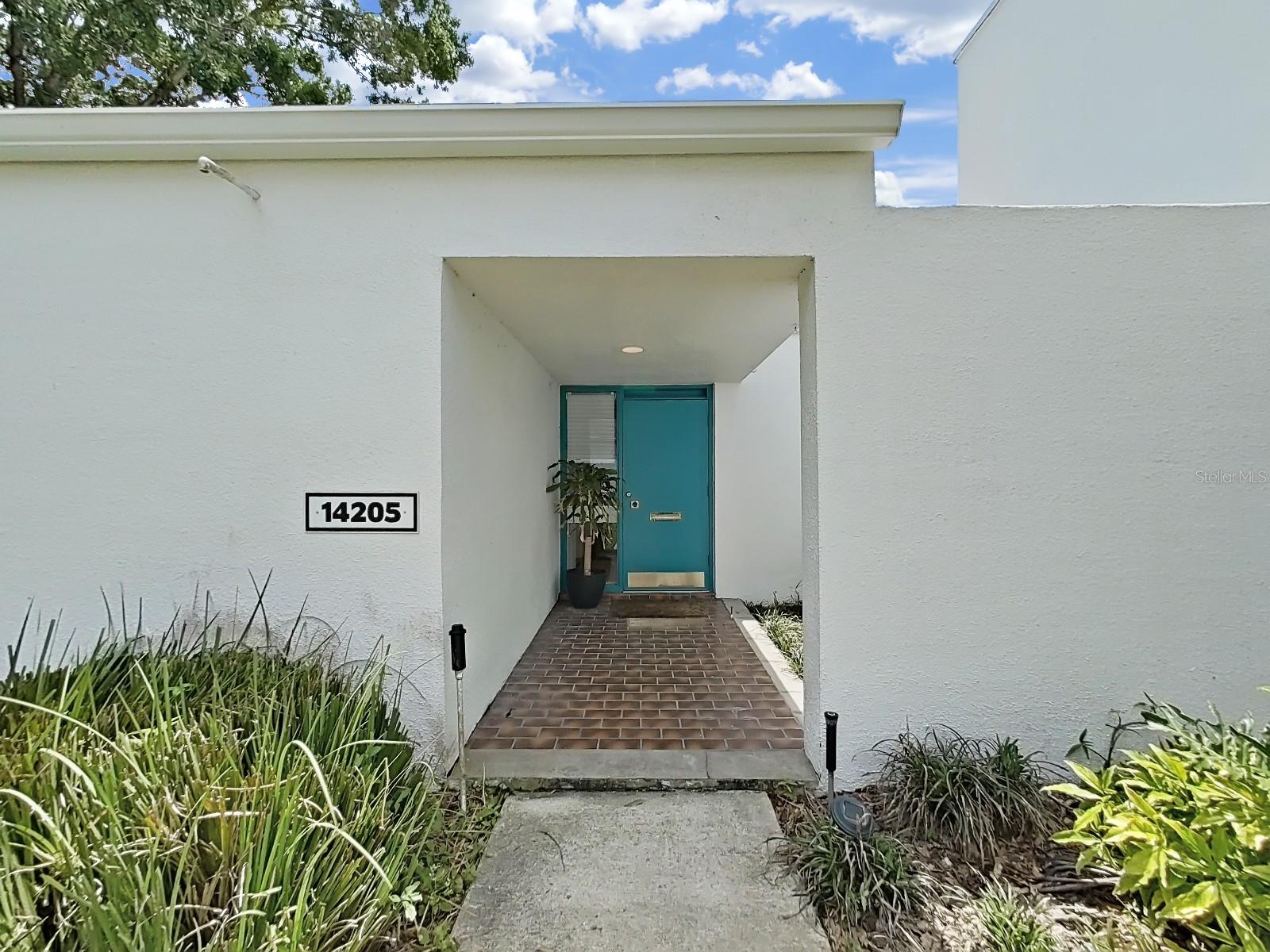 Covered front porch with decorative floor and landscaped courtyard.