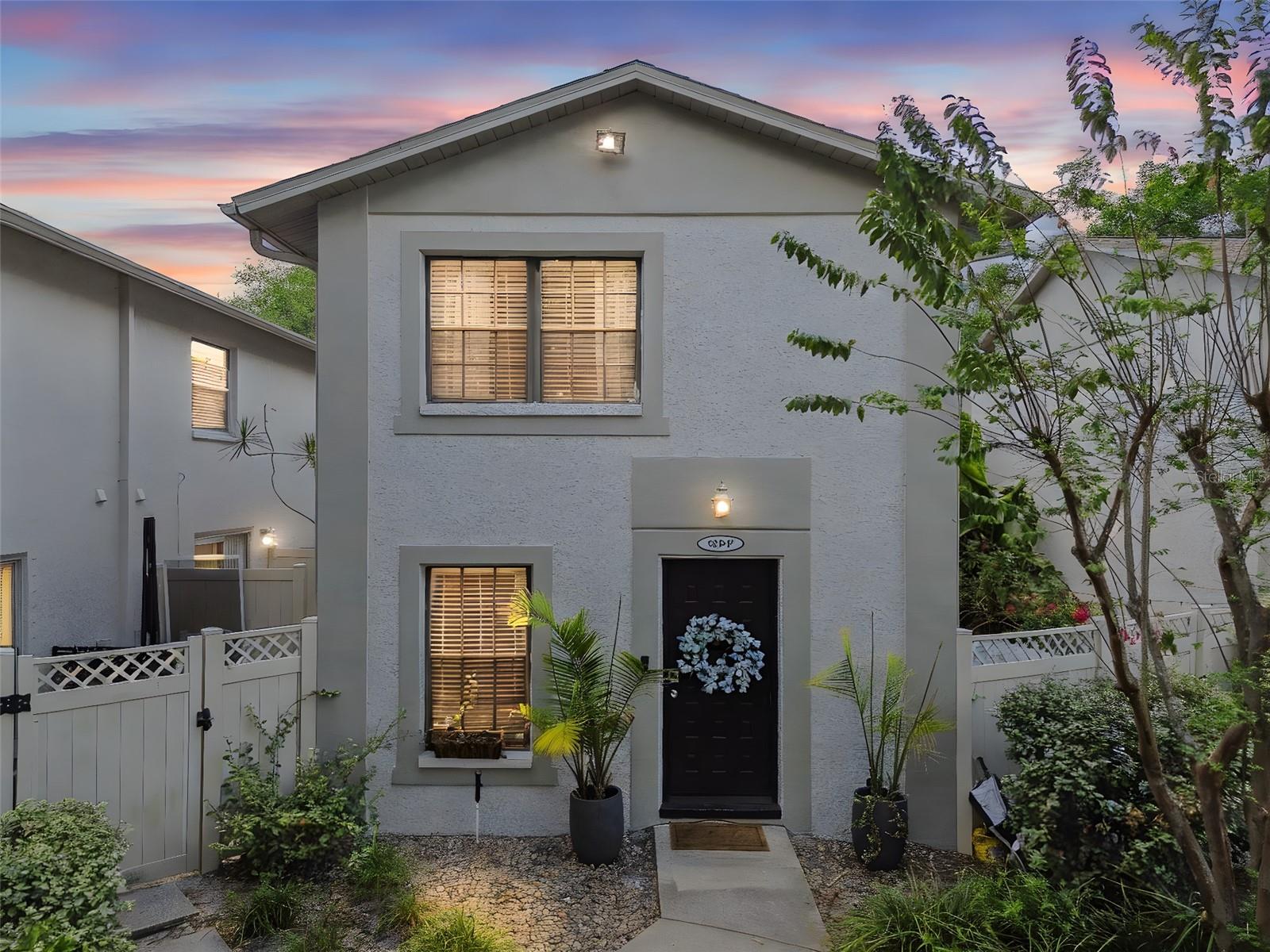 Private townhouse entrance with sleek black door, decorative planter accents, and low-maintenance pebble landscaping.