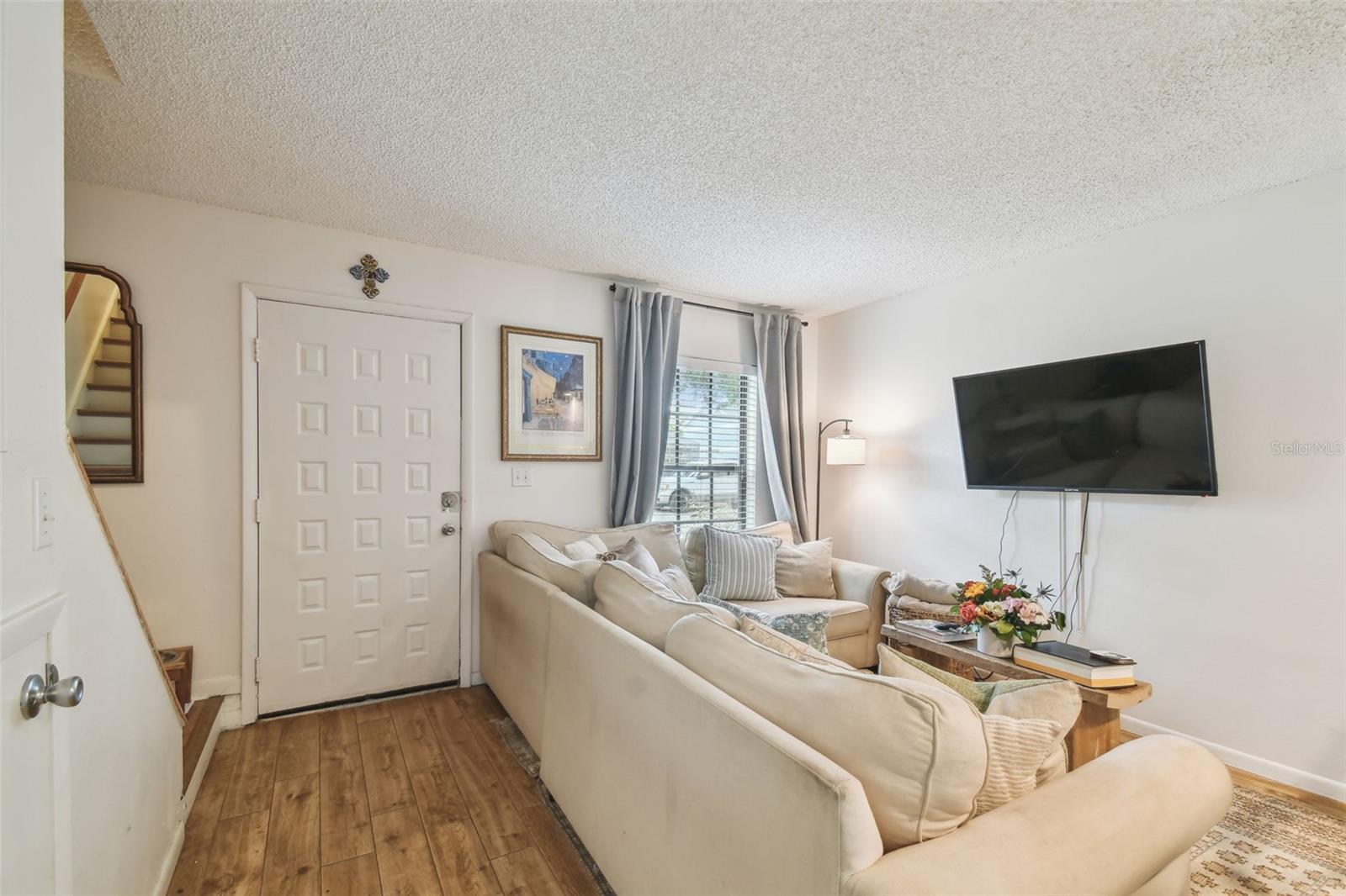 Cozy seating area with wood-look flooring, natural light from front window.