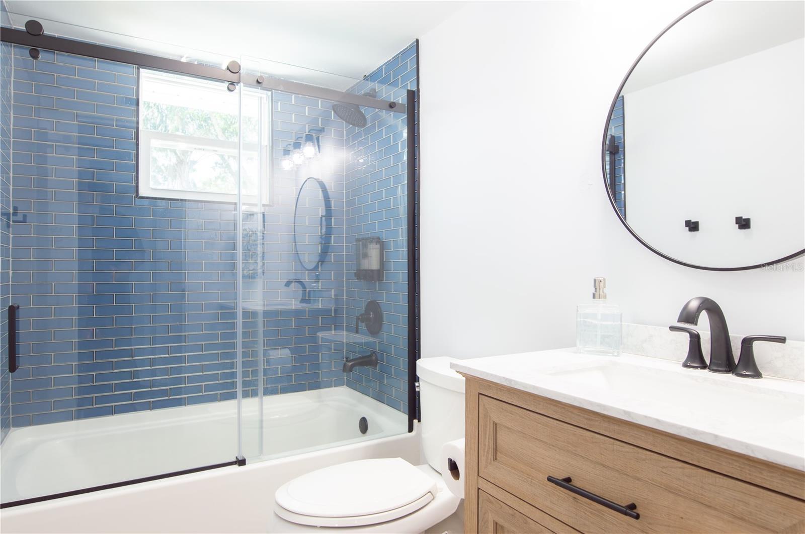 BEAUTIFULLY REMODELED GUEST BATHROOM WITH GLASS TILES & SHOWER DOOR.