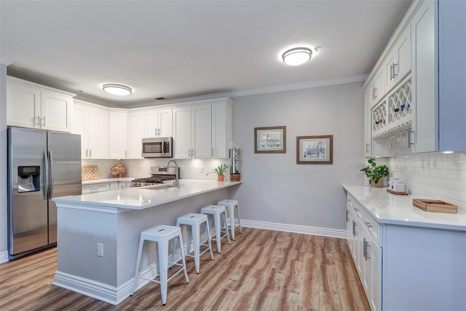 View of the front entry hall and the wine/coffee or dry bar with a wall of 42" upper and lower cabinets, wine rack, quartz counter tops, wine/beverage refrigerator to the far left