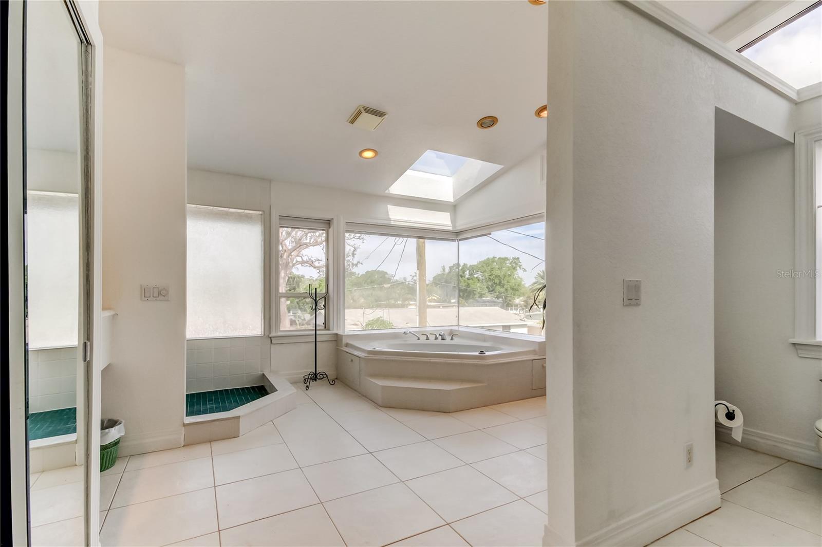 Primary bath with shower, jacuzzi tub closet and toilet room .
