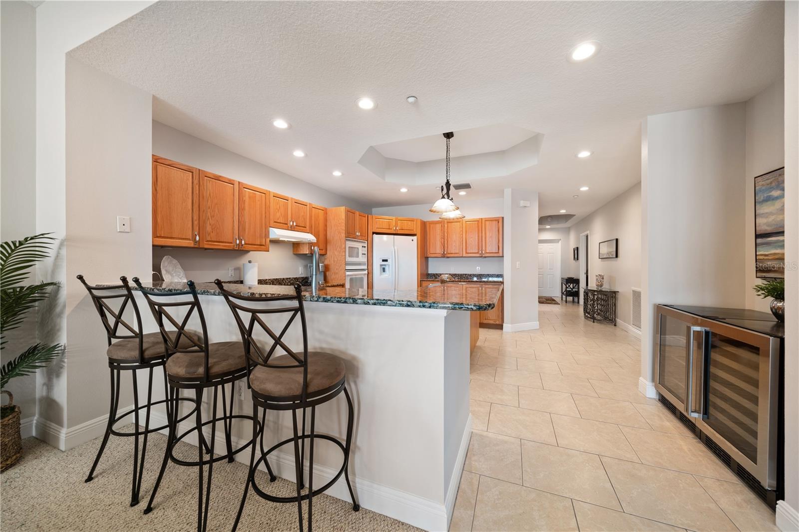 The kitchen has an abundance of cabinetry a dryer wine area barstool seating , spacious island and large  laundry room with pantry closet space across the hallway