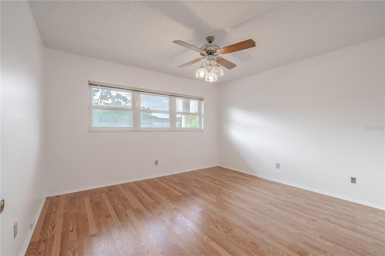 The 2nd bedroom features freshly painted neutral tone walls, new wood laminate flooring and a ceiling fan with light kit.