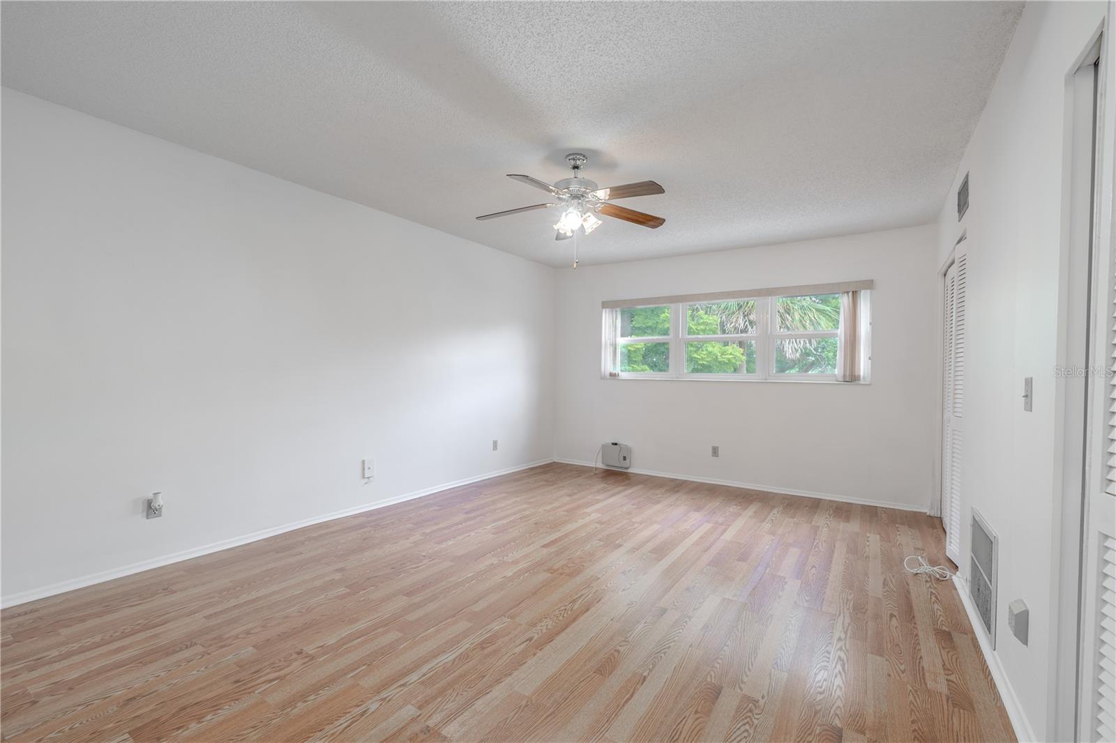 Primary bedroom features freshly painted neutral tone walls, new wood laminate flooring and a ceiling fan with light kit.