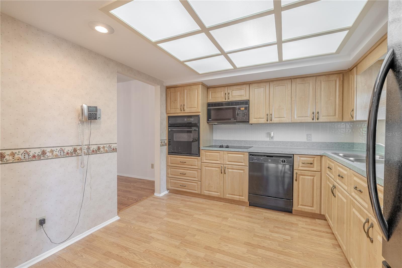 The kitchen features overhead lighting, a suite of appliances including a built in oven, electric cooktop, a microwave, dishwasher and refrigerator.