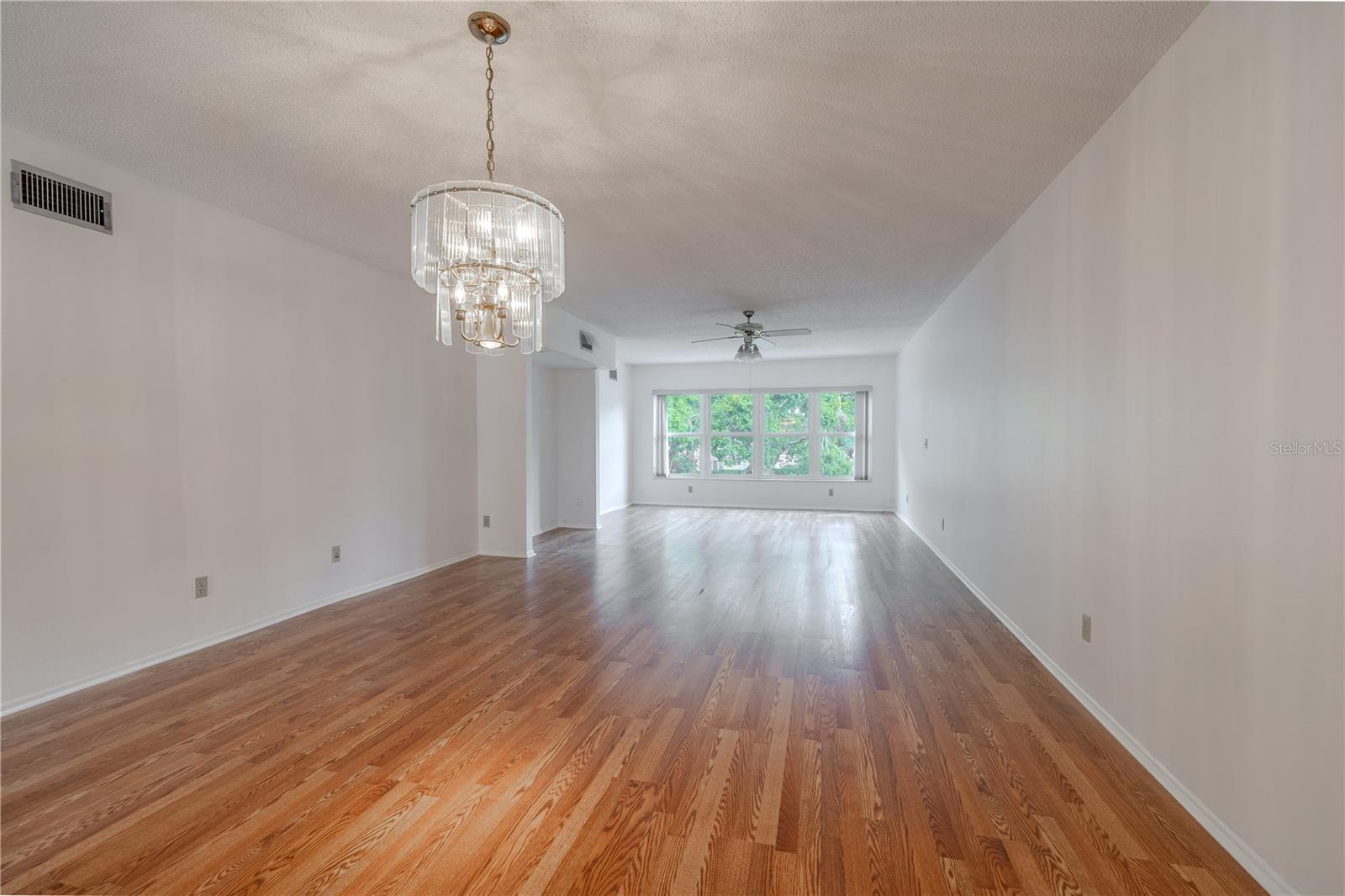 The dining room features a pendant chandelier, freshly painted neutral tone walls and new wood laminate flooring.