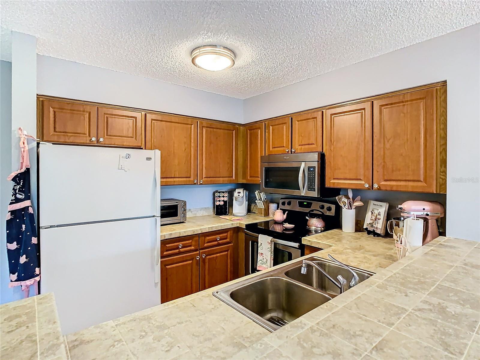 Spacious tiled counters and wood cabinetry in Kitchen.
