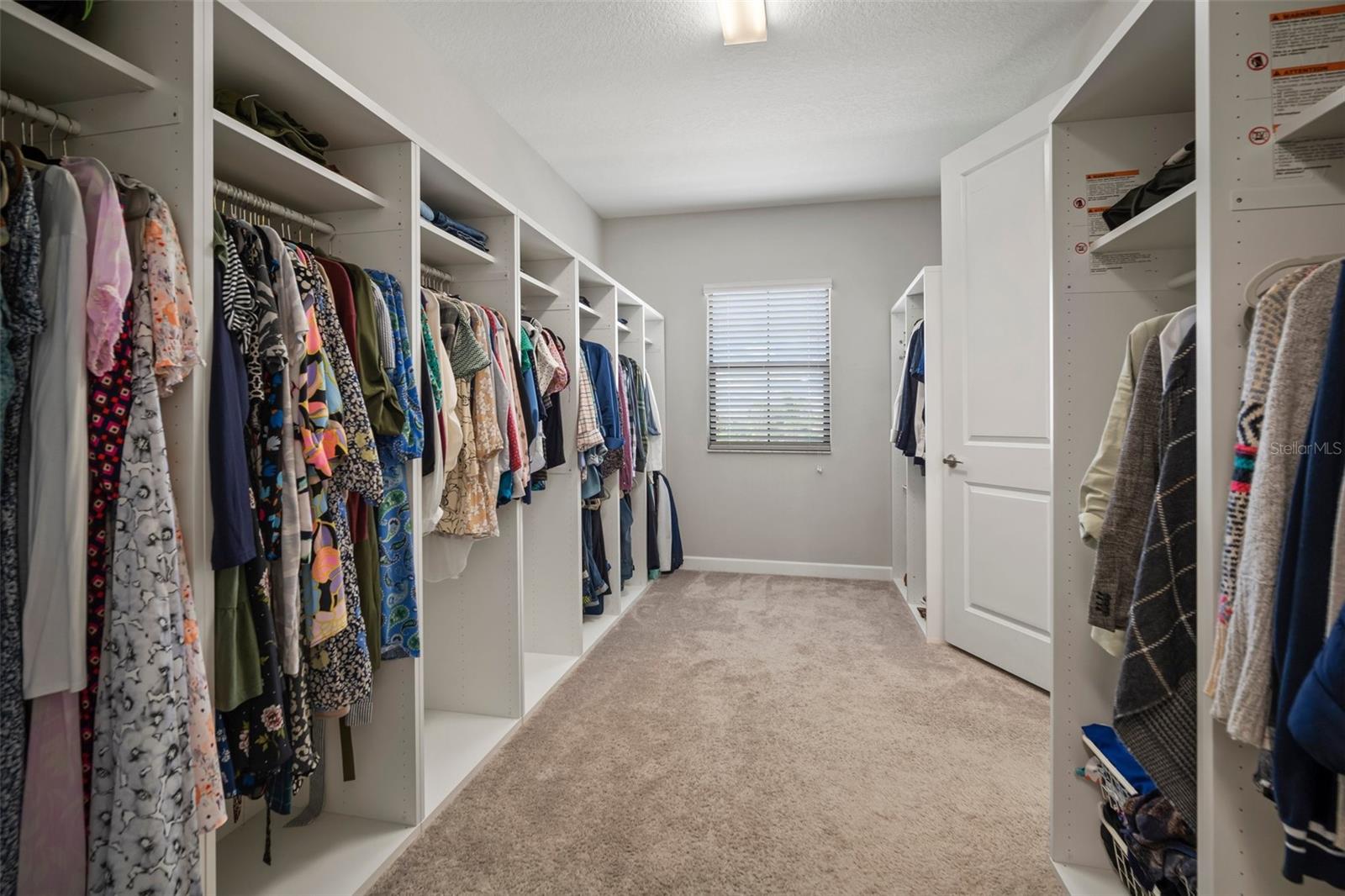 Primary oversized walk-in closet with custom built-in shelving