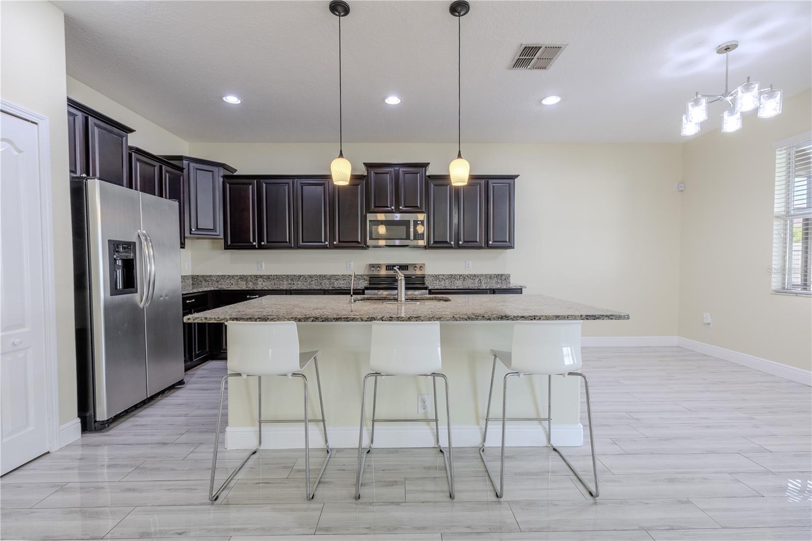 The kitchen features a suite of GE clean-steel kitchen appliances including a French door refrigerator with ice maker and water dispenser, dishwasher, range and microwave.