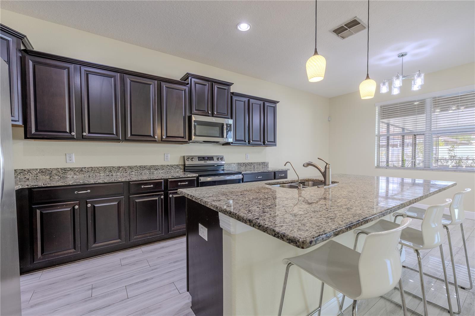 The kitchen island features seating for 3-4, and artistic pendant lights thank hang above.