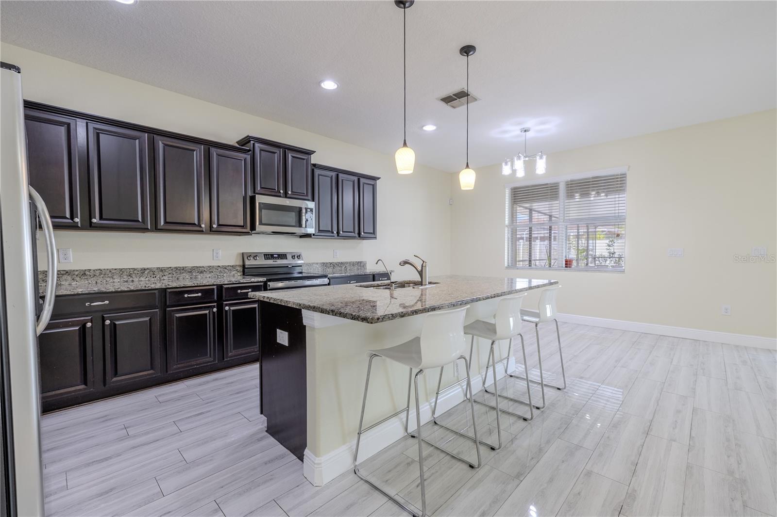The kitchen island features a stainless steel sink and granite countertop.